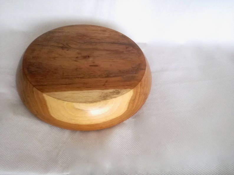 K&ouml;nnte beinhalten: Eine runde Holzschale mit hellbrauner Farbe und einem dunkelbraunen Rand. Die Schale ist aus Naturholz gefertigt und hat eine glatte, polierte Oberfl&auml;che.