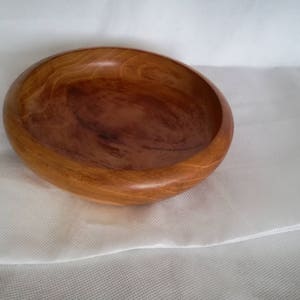 K&ouml;nnte beinhalten: Eine Holzschale mit nat&uuml;rlicher brauner Oberfl&auml;che. Die Schale ist rund und hat eine leichte W&ouml;lbung an den Seiten. Sie ist aus einem einzigen St&uuml;ck Holz gefertigt und hat eine glatte, polierte Oberfl&auml;che.