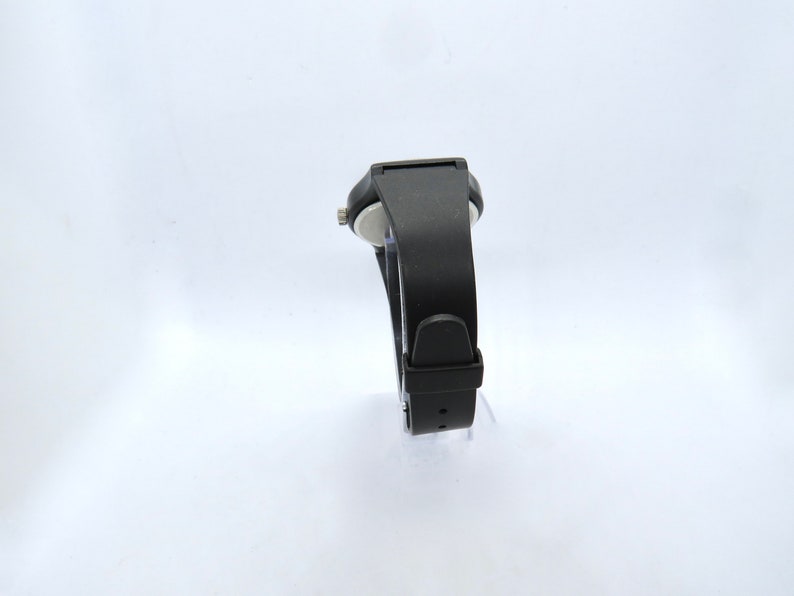 K&ouml;nnte beinhalten: Eine schwarze Armbanduhr mit rechteckigem Zifferblatt und schwarzem Armband. Die Uhr hat ein schlichtes, modernes Design mit einem Schnallenverschluss. Die Uhr wird vor einem wei&szlig;en Hintergrund pr&auml;sentiert.