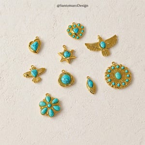 Peut inclure: Une collection de pendentifs dor&eacute;s avec des pierres de couleur turquoise. Les pendentifs pr&eacute;sentent diverses formes, notamment un c&oelig;ur, une &eacute;toile, un oiseau et une fleur. Les pendentifs sont dispos&eacute;s sur une surface de couleur claire. Le texte "@SantomaroDesign" est en haut &agrave; gauche.