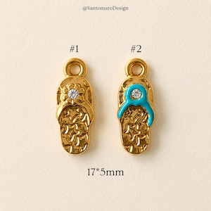 May include: Two gold-colored metal flip-flop charms. One features a flower with a clear crystal, the other has a turquoise strap and a clear crystal. The charms are 17mm x 5mm. The text "@SantomaroDesign" is at the top.