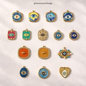 Puede incluir: Una colección de colgantes dorados con varios diseños de ojos. Los colgantes presentan esmalte colorido y detalles de cristal, con formas cuadradas, rectangulares, ovaladas y de corazón. La imagen incluye el texto "@SantoromaroDesign".