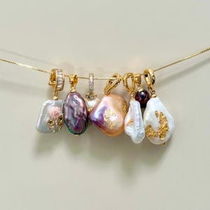 May include: A selection of gold necklaces, each with a distinctive, freeform pearl pendant. The pearls vary in colour, from white to lavender and peach, with gold detailing. The text "@SantomaroDesign" is visible at the top of the image.