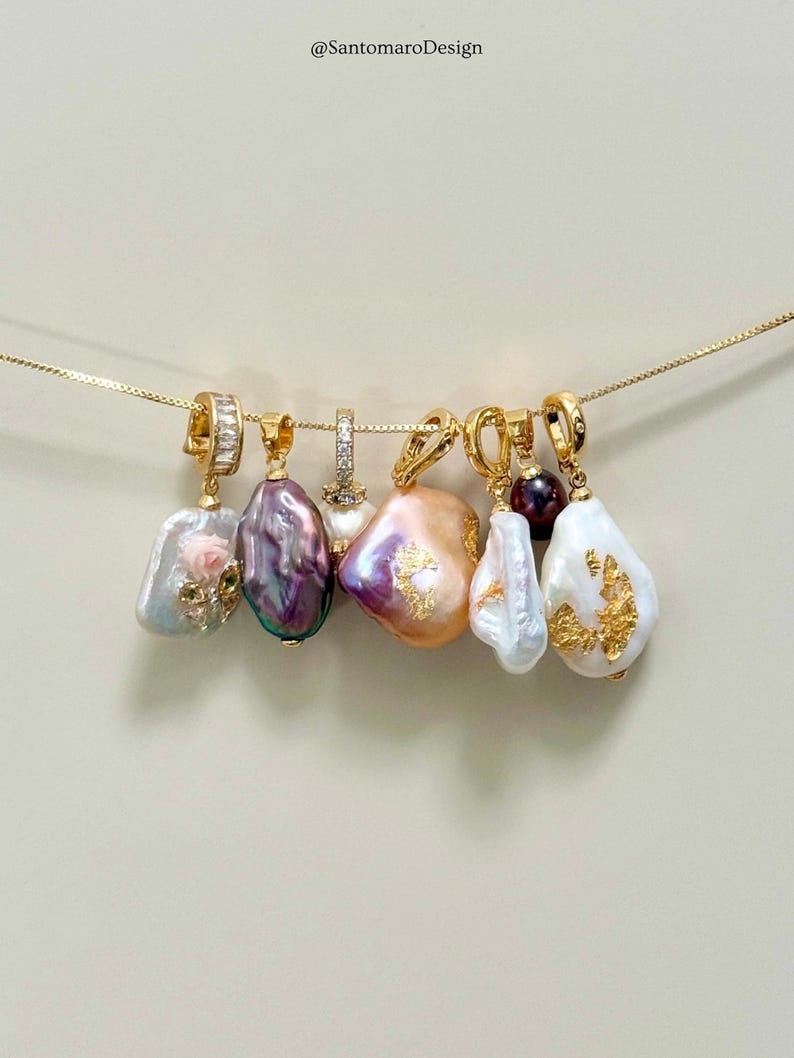May include: A selection of gold necklaces, each with a distinctive, freeform pearl pendant. The pearls vary in colour, from white to lavender and peach, with gold detailing. The text "@SantomaroDesign" is visible at the top of the image.