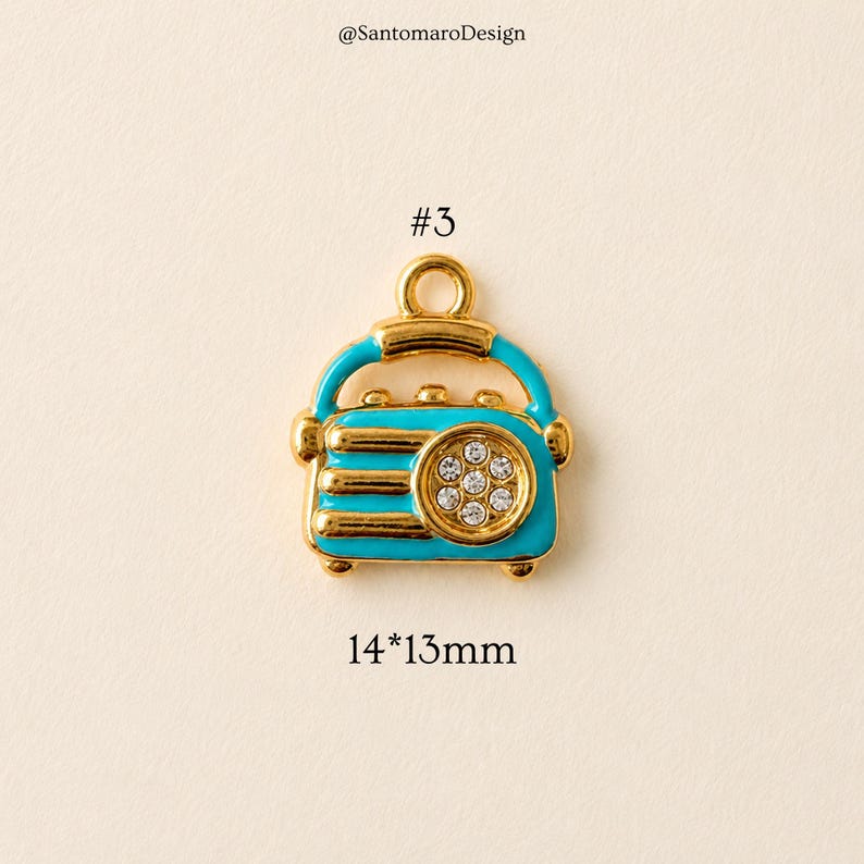 May include: A gold-toned charm in the shape of a vintage radio, with a turquoise blue body and gold accents. The radio has a circular design with clear crystals and measures 14mm x 13mm.