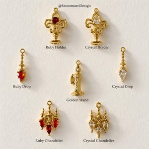 Peut inclure: Une collection de breloques de bijoux dorés. Les breloques comprennent un porte-rubis, un porte-cristal, une goutte de rubis, une goutte de cristal, un support doré, un lustre de rubis et un lustre de cristal. Le texte "@SantomaroDesign" est visible.
