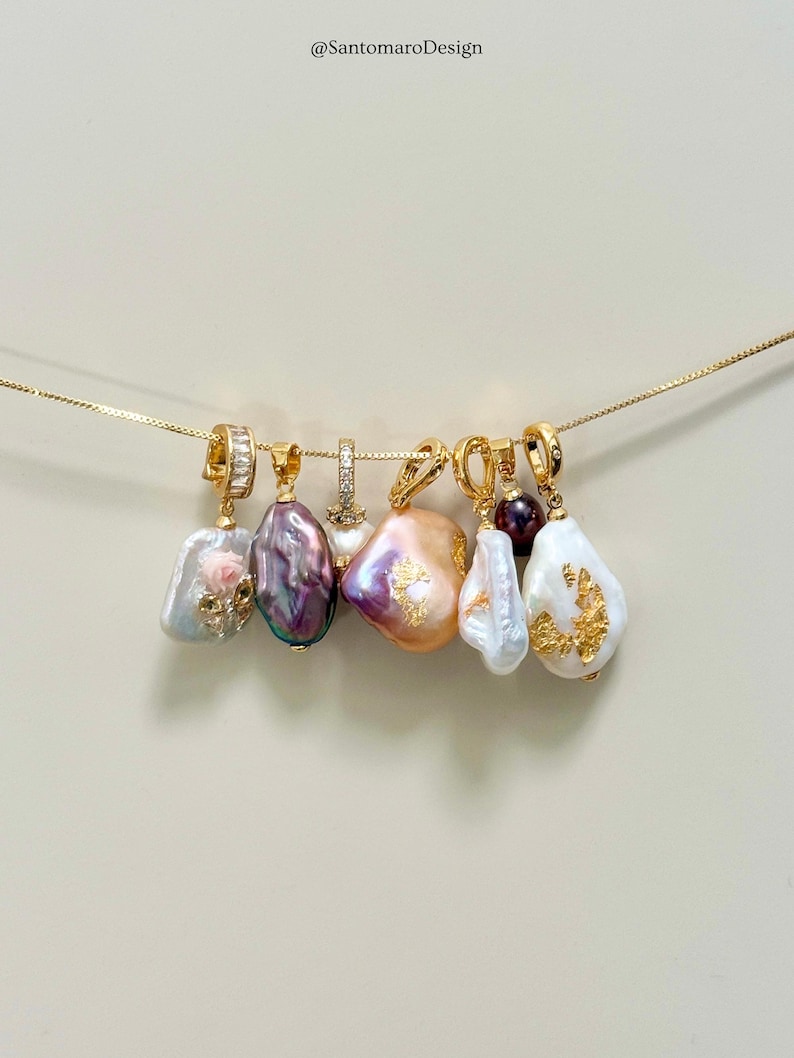 May include: A selection of gold pendants, each featuring a baroque pearl in colours like white, pink, purple, and peach. The pearls have gold detailing and hang from a fine gold chain.