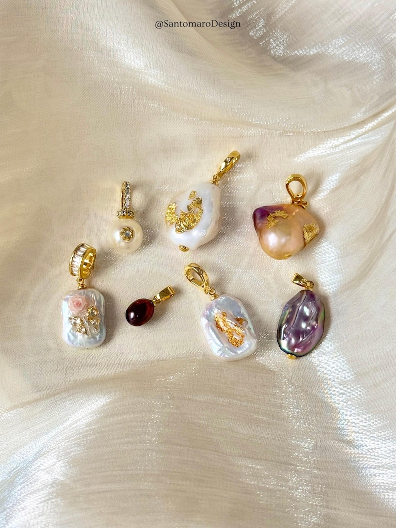 May include: A selection of gold-plated pendants featuring pearls and gemstones. The pendants showcase baroque pearls with gold detailing, a pearl with a diamond-set bale, and a rectangular pendant with a floral design.