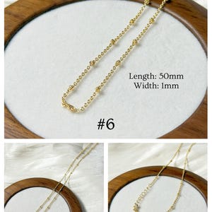 Op de afbeelding: Een delicate goudkleurige ketting met kleine, gelijkmatig verdeelde kralen. De ketting is 50 mm lang en 1 mm breed. De afbeelding bevat de tekst "#6" en de tekst "Lengte: 50 mm Breedte: 1 mm". De ketting wordt op een wit oppervlak getoond.
