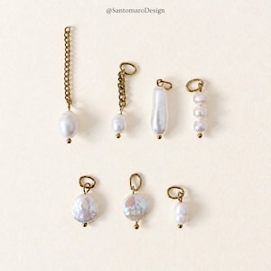 May include: Seven jewelry charms featuring white freshwater pearls and gold-toned metal components. The collection includes various shapes of pearls, some attached to short gold chains and others suspended directly from small circular jump rings.