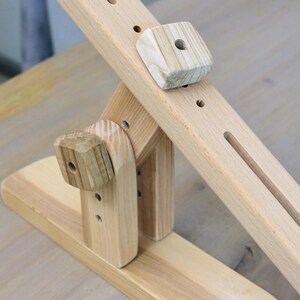 K&ouml;nnte beinhalten: Ein Holzspielzeug mit einem Hebel und einem Block. Das Spielzeug ist aus Naturholz gefertigt und hat ein schlichtes Design.