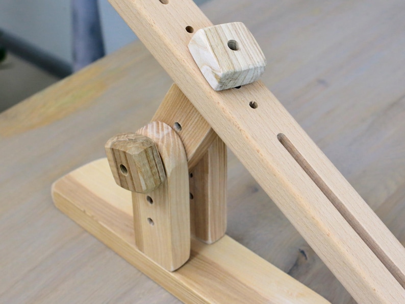 K&ouml;nnte beinhalten: Ein Holzspielzeug mit einem Hebel und einem Block. Das Spielzeug ist aus Naturholz gefertigt und hat ein schlichtes Design.