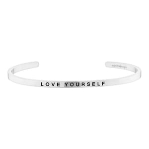 Könnte beinhalten: Silbernes Armreif-Armband mit der Aufschrift "LOVE YOURSELF" in schwarzen Buchstaben.