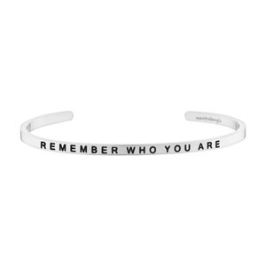 May include: Silver bangle bracelet inscribed with the words "REMEMBER WHO YOU ARE" in black lettering.