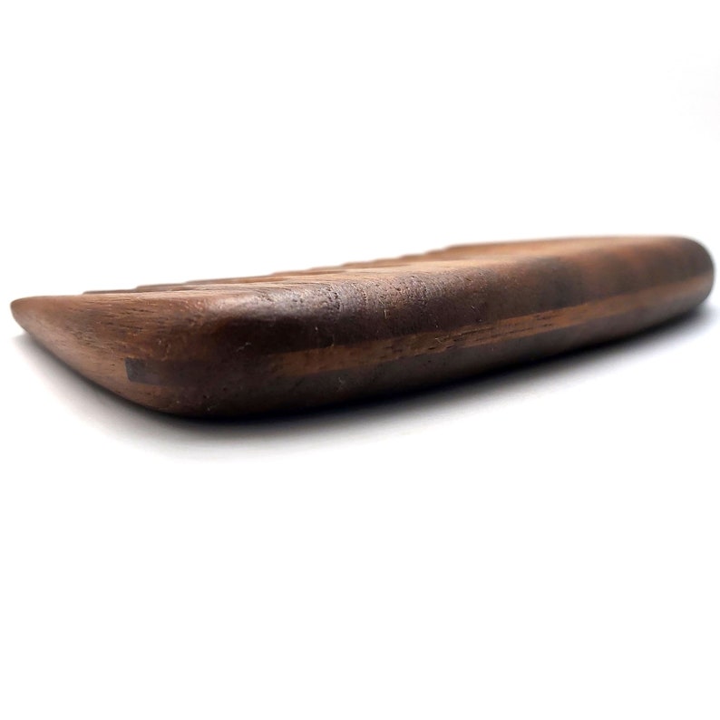 Puede incluir: Un primer plano de un peine de madera marr&oacute;n oscuro con una superficie lisa y redondeada. El peine tiene un patr&oacute;n de veta de madera natural y est&aacute; hecho de una sola pieza de madera.