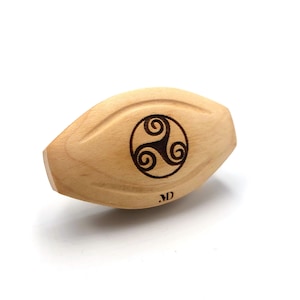 Puede incluir: Un objeto de madera de forma ovalada con un diseño de nudo celta quemado en la superficie. El objeto está hecho de madera clara y tiene un acabado liso. El diseño del nudo está en el centro del objeto y está rodeado por un círculo. El objeto está etiquetado con las iniciales "M.D."