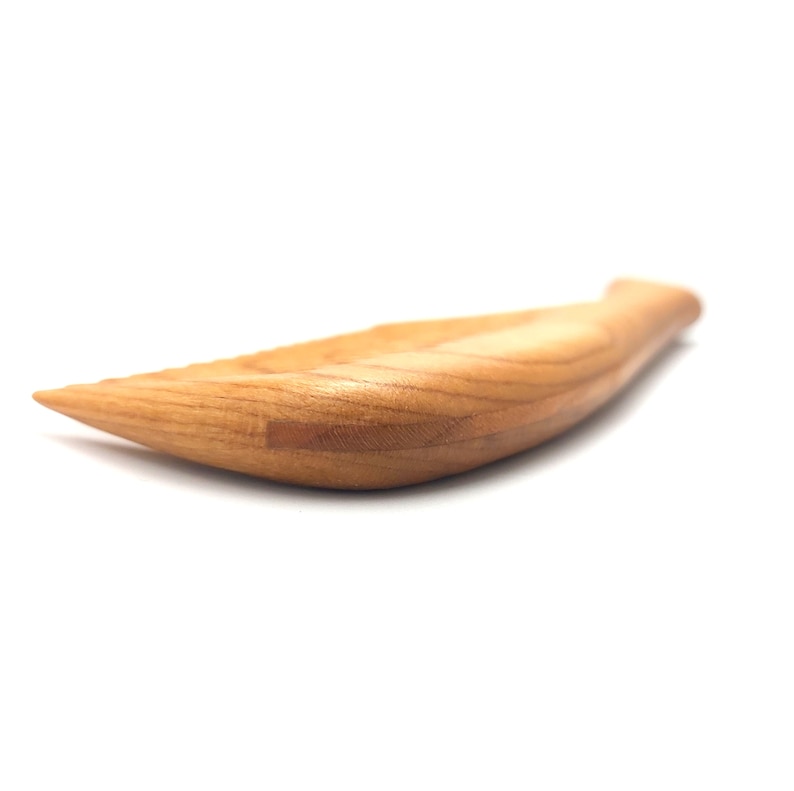 Pode incluir: Um prato de servir de madeira em forma de peixe. O prato &eacute; feito de madeira castanho claro e tem um acabamento liso e polido.