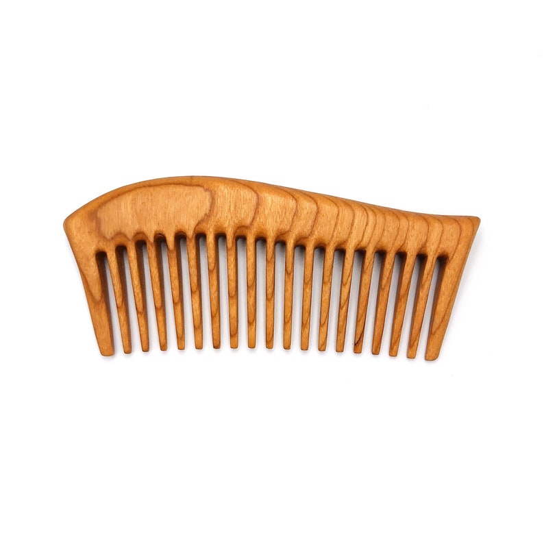 May include: A wooden comb with a curved handle and fine teeth. The comb is made of light brown wood with a natural grain pattern.