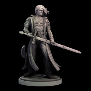May include: A gray painted miniature figurine of a person wearing a long coat and holding a sword. The figurine is standing on a round base.