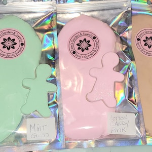 May include: Three sealed bags of colorful dough, each with a gingerbread man cutout. The bags are labeled "Mint Green", "Cotton Candy Pink", and "Cookie Dough Gingerbread". Each bag has a circular logo with text.