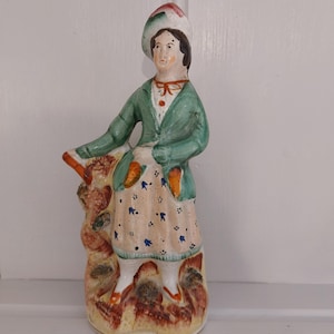 Figura antigua de porcelana Pearlware de Staffordshire que representa a una dama de pie sobre una loma rocosa, circa 1800.