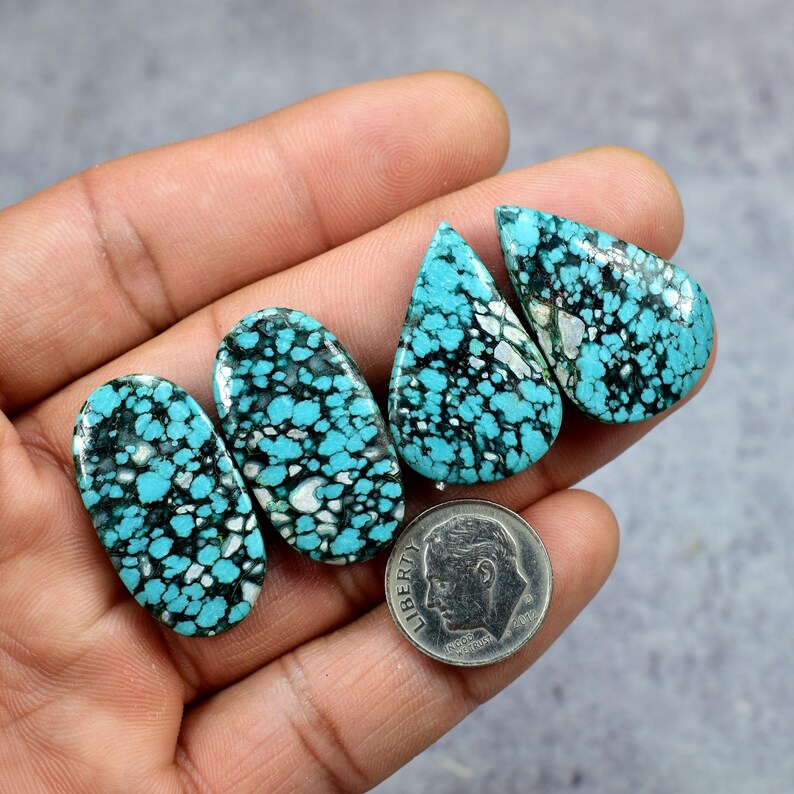 Puede incluir: Cuatro piedras preciosas turquesas con patrones de matriz negros y blancos. Las piedras tienen varias formas, incluyendo ovaladas y en forma de l&aacute;grima. Se incluye una moneda para comparar el tama&ntilde;o. Las piedras preciosas se sostienen en una mano.