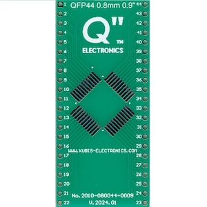 May include: A green printed circuit board with a Q"TM" ELECTRONICS logo and the text "QFP44 0.8mm 0.9" 44" and "WWW.KUBIS-ELECTRONICS.COM". The board has a diamond-shaped pattern of pins and the text "No. 2010-080044-0009 V. 2024.01".