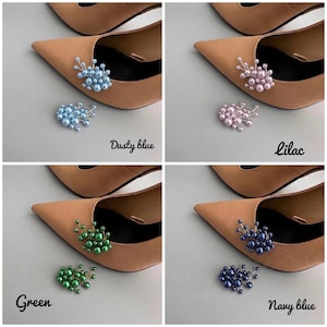 May include: Four pairs of tan pointed-toe heels, each adorned with a cluster of decorative pearls. The clusters are in dusty blue, lilac, green, and navy blue. The colors are labeled in the image.
