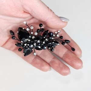 May include: A decorative hair accessory featuring a cluster of black teardrop-shaped crystals, small round black beads, and clear sparkling rhinestones set on thin, flexible black wire branches that extend outward in a spray pattern.