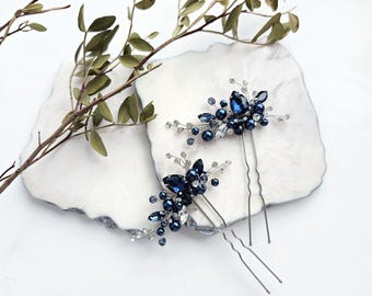 May include: Two silver-toned hair pins featuring clusters of deep navy blue teardrop crystals, round dark blue beads, and small clear rhinestones arranged on thin, flexible wire branches. Each pin has a two-pronged metal base for secure placement.