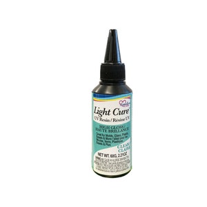 May include: A clear bottle of UV resin for crafting. The bottle is labeled "Light Cure UV Resin/Résine UV" and "High Gloss/Haute Brillance". The bottle is 60 grams or 2.21 ounces.