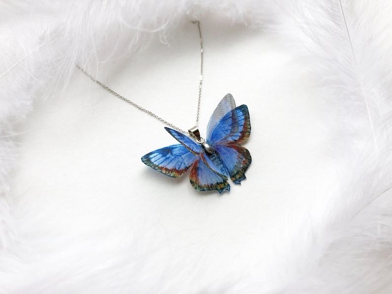 Blue butterfly necklace on white feathers background