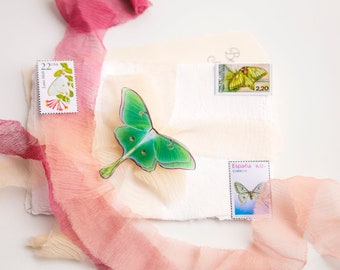 May include: A white envelope with three postage stamps featuring butterflies. The stamps are from the United States, Spain, and another country. The envelope is decorated with a pink and beige fabric.