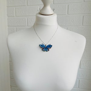 Blue butterfly pendant necklace with silver chain on white background