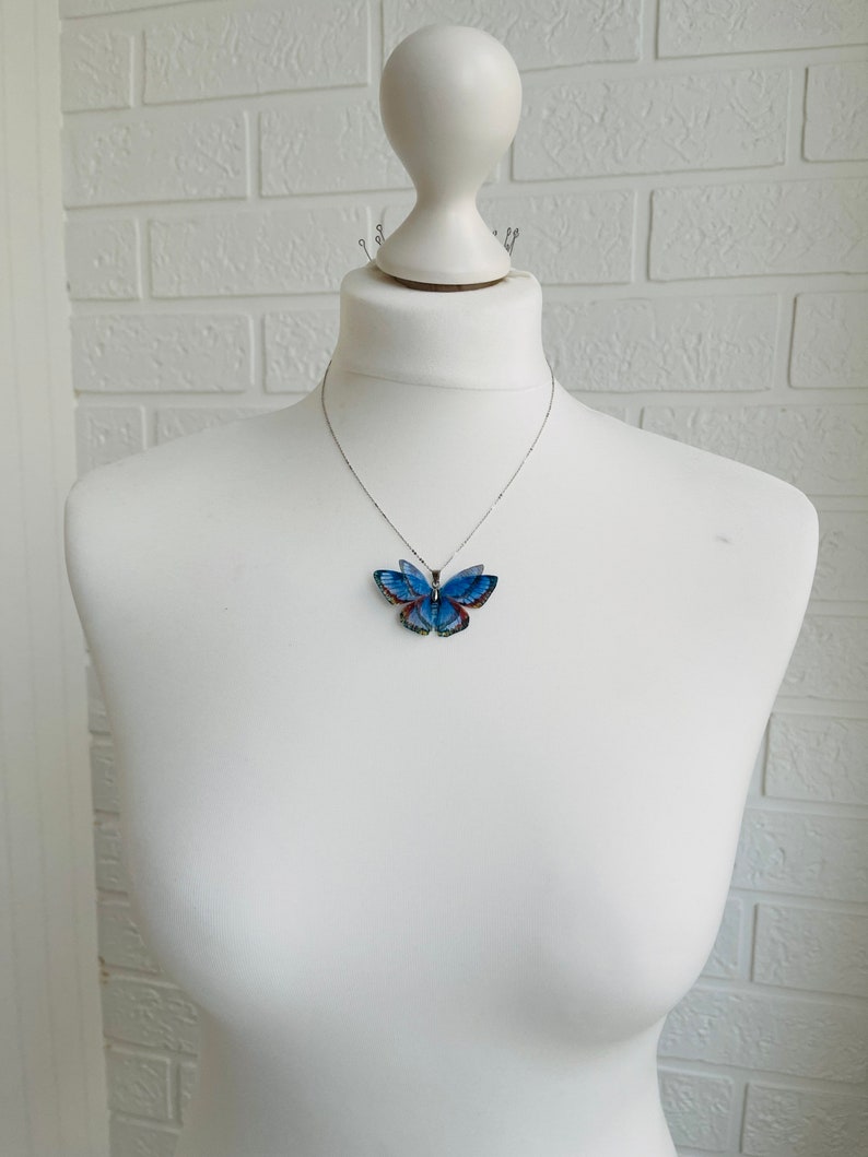 Blue butterfly pendant necklace with silver chain on white background