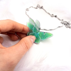 Green Lunar Moth Pendant with chain on a nature-inspired background - Show off your love for the environment with this eco-friendly jewelry piece