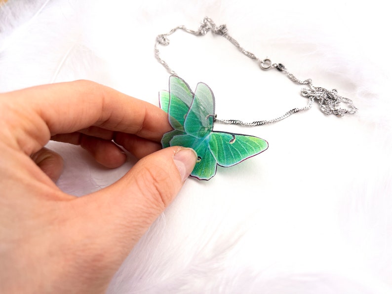 Green Lunar Moth Pendant with chain on a nature-inspired background - Show off your love for the environment with this eco-friendly jewelry piece