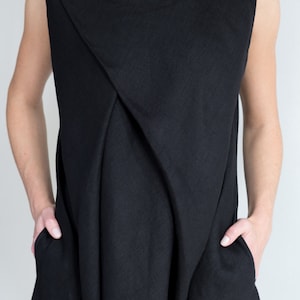 May include: A black sleeveless dress with a draped neckline and pockets.