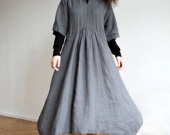 May include: A gray linen dress with a v-neck and 3/4 sleeves. The dress has a gathered waist and a flowing skirt.