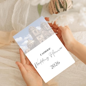 May include: A white Catholic Wedding Planner for 2026, held by hands. The cover features a church image under a blue sky with clouds. The words "Catholic Wedding Planner" are written in elegant script.