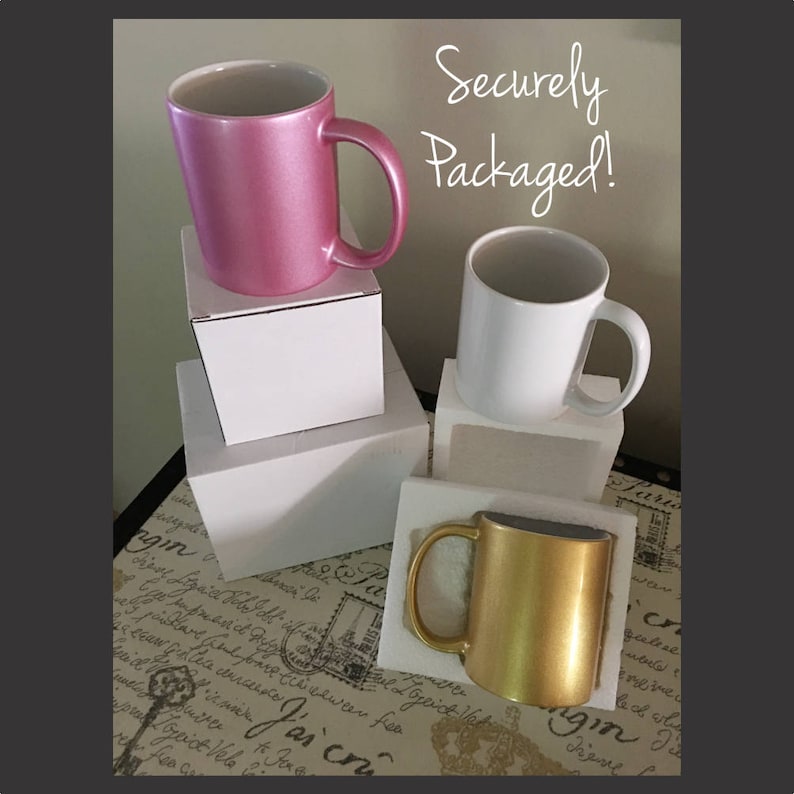 May include: Three ceramic mugs in pink, white, and gold are displayed on white boxes. The text "Securely Packaged!" is written in black marker on a white background.