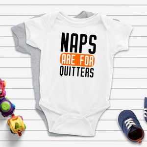 May include: White baby onesie with black text that reads "Naps are for quitters". The text "are for" is in an orange rectangle.