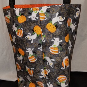 May include: A black and gray Halloween tote bag with a repeating pattern of white ghosts and orange pumpkins. The bag has black straps.