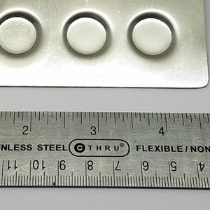 May include: A close-up of a silver ruler with black markings, measuring 6 inches. The ruler is labeled "MR-6 Stainless Steel Thru Flexible/Non-Skid Made in China".