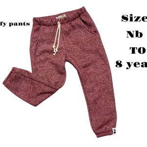 May include: Maroon comfy trousers with a drawstring waist and pockets. The text "Comfy pants" is on the left, and "Size Nb to 8 years" is on the right. These trousers are designed for children.