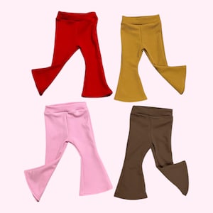 May include: Four pairs of baby or toddler flare pants in red, mustard yellow, pink, and brown. The pants have a high waist and a flared leg design. The fabric appears to be soft and stretchy, suitable for comfort and movement.