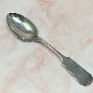 May include: A silver spoon with an ornate handle. The handle is engraved with the text "Samuel C. Davis".