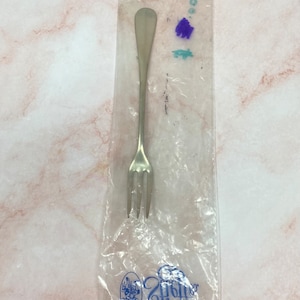 May include: A silver fork in a clear plastic bag with a blue and white logo that says "Gifts"