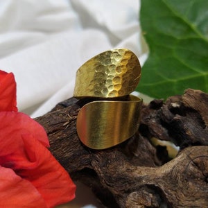 May include: A gold hammered metal ring with a curved design. The ring is open and adjustable.