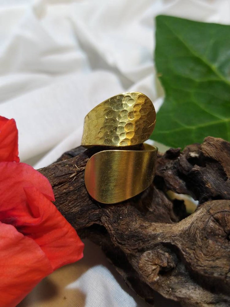 May include: A gold hammered metal ring with a curved design. The ring is open and adjustable.